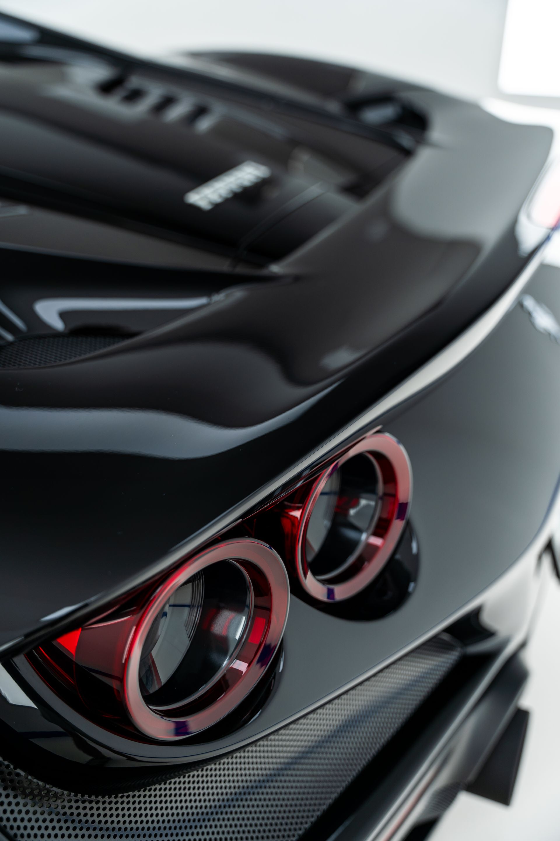 Close-up of a black sports car rear with dual round taillights and glossy bodywork
