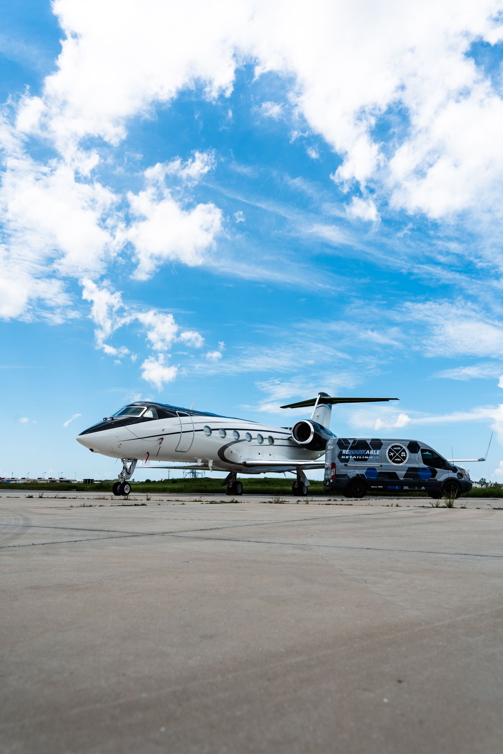 Two small twin-engine planes on a runway under a bright blue sky with scattered clouds