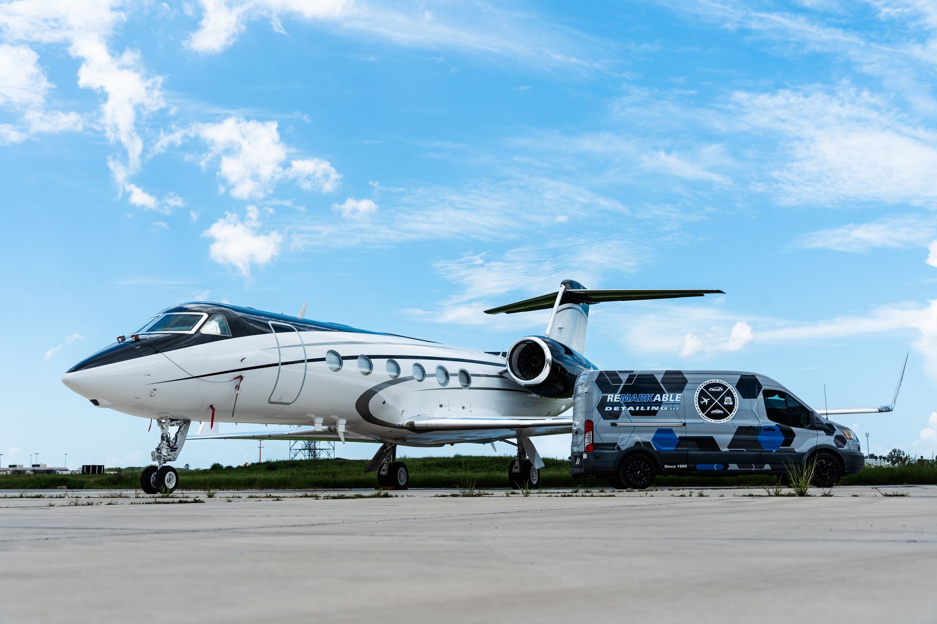 White and blue airplane on a runway beside a blue maintenance truck under a cloudy sky