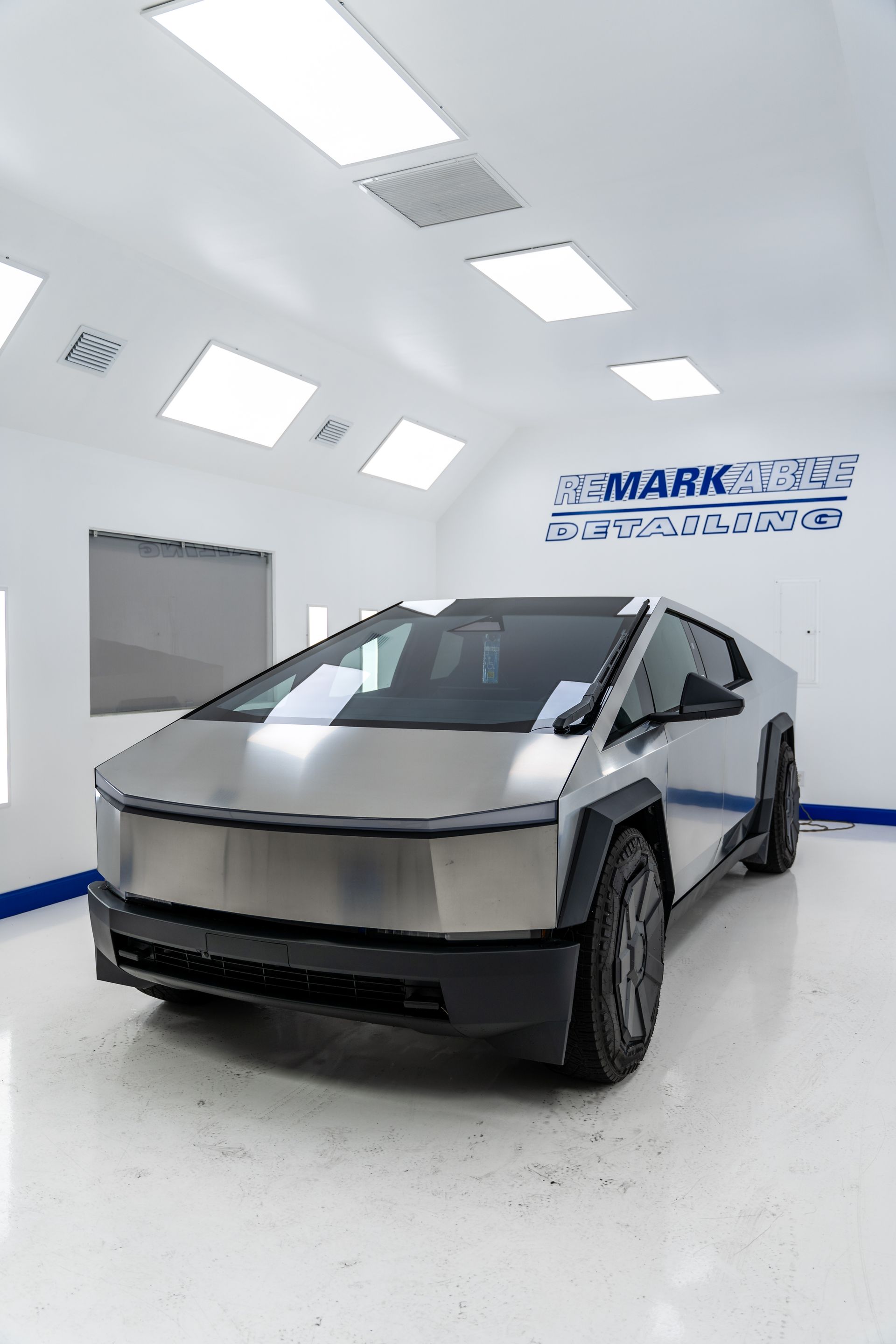 Silver Tesla Cybertruck in a bright white showroom with glossy floors and wall branding