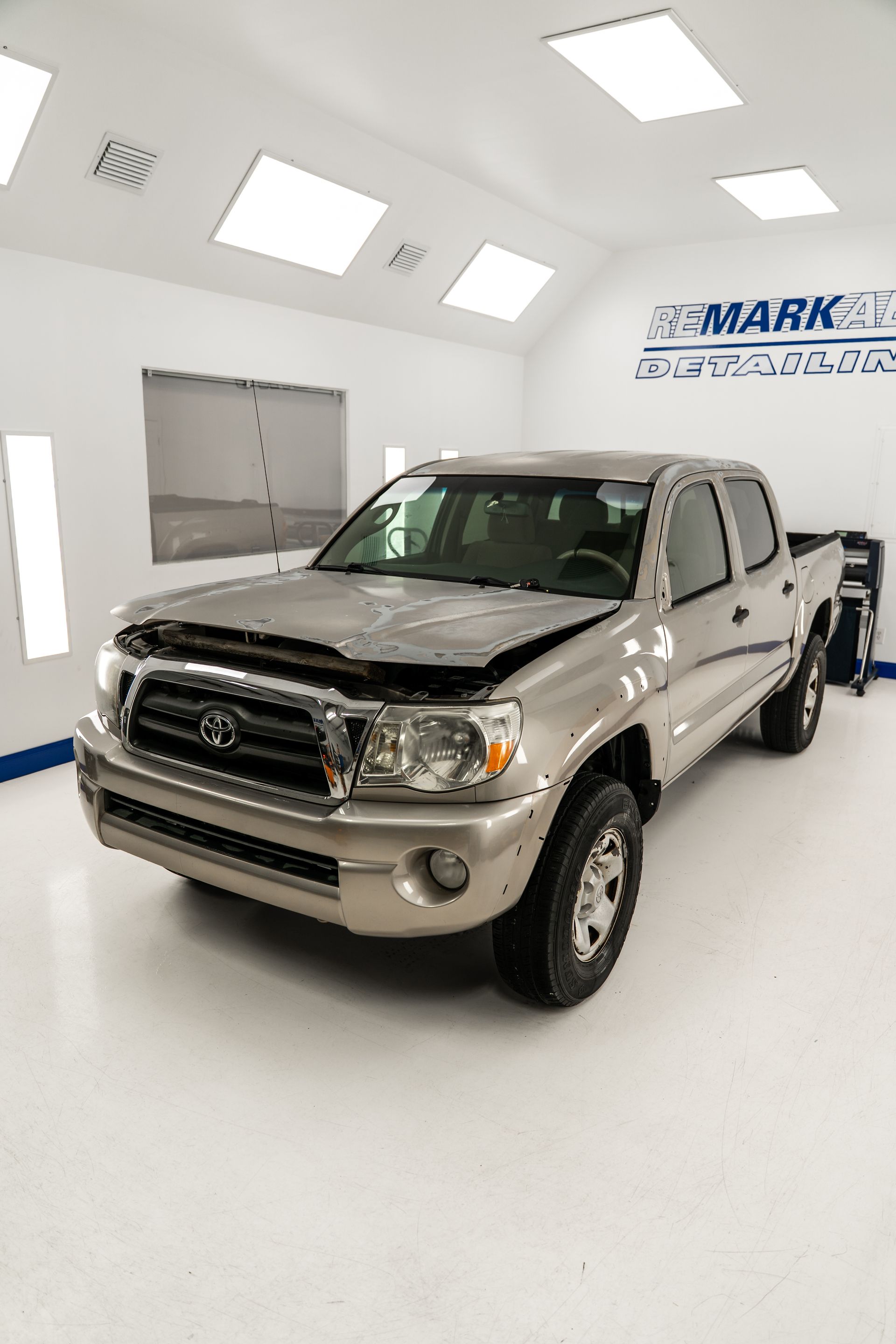 Silver Ford pickup truck in a bright white showroom, angled front view