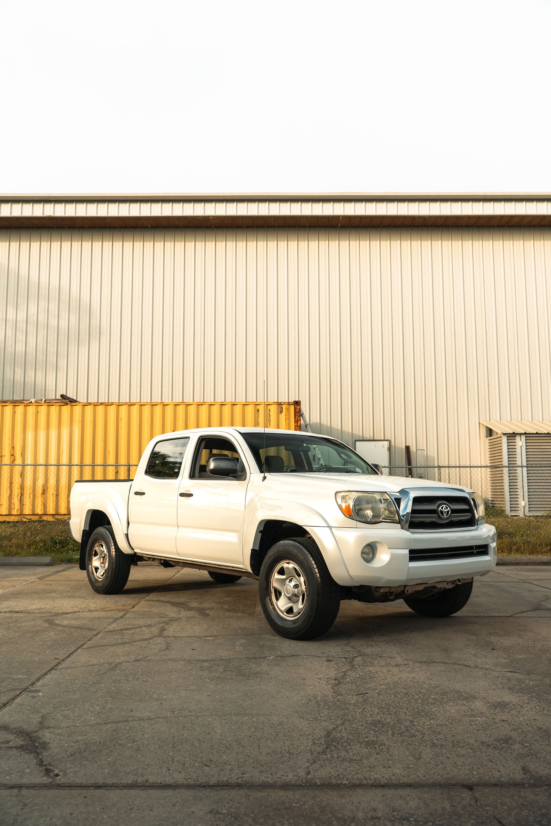 White pickup truck parked in front of a beige warehouse building