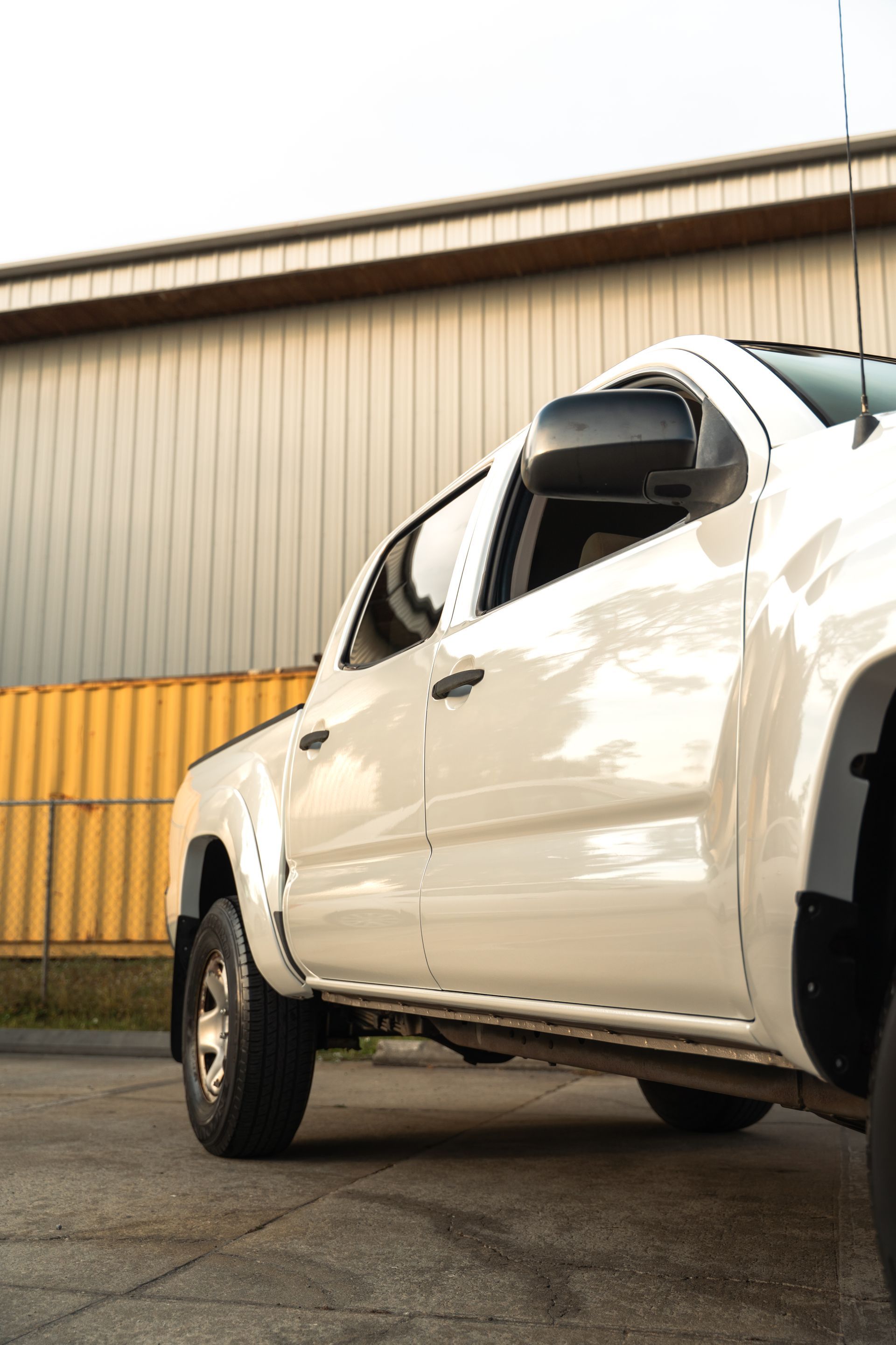 White pickup truck parked beside a yellow warehouse wall