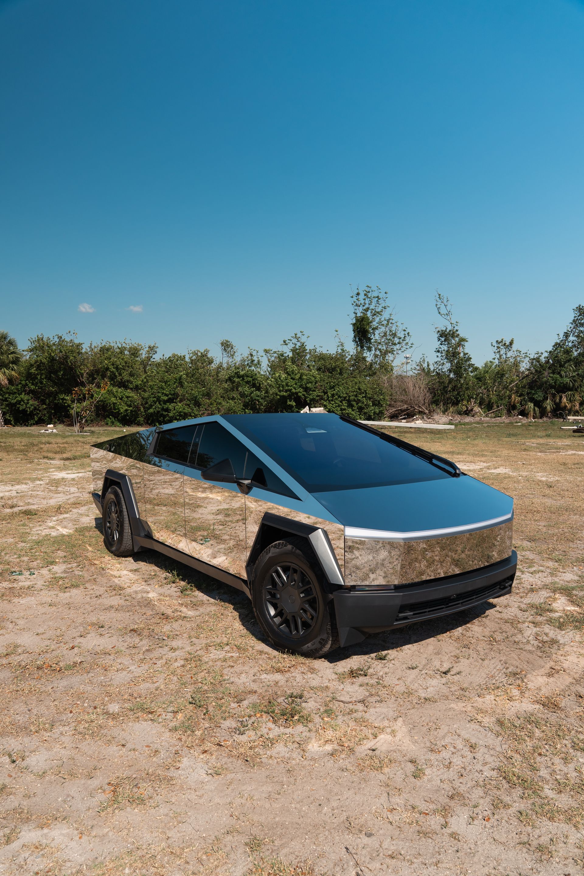 Futuristic silver pickup truck with a blue windshield parked on dry ground under a clear blue sky
