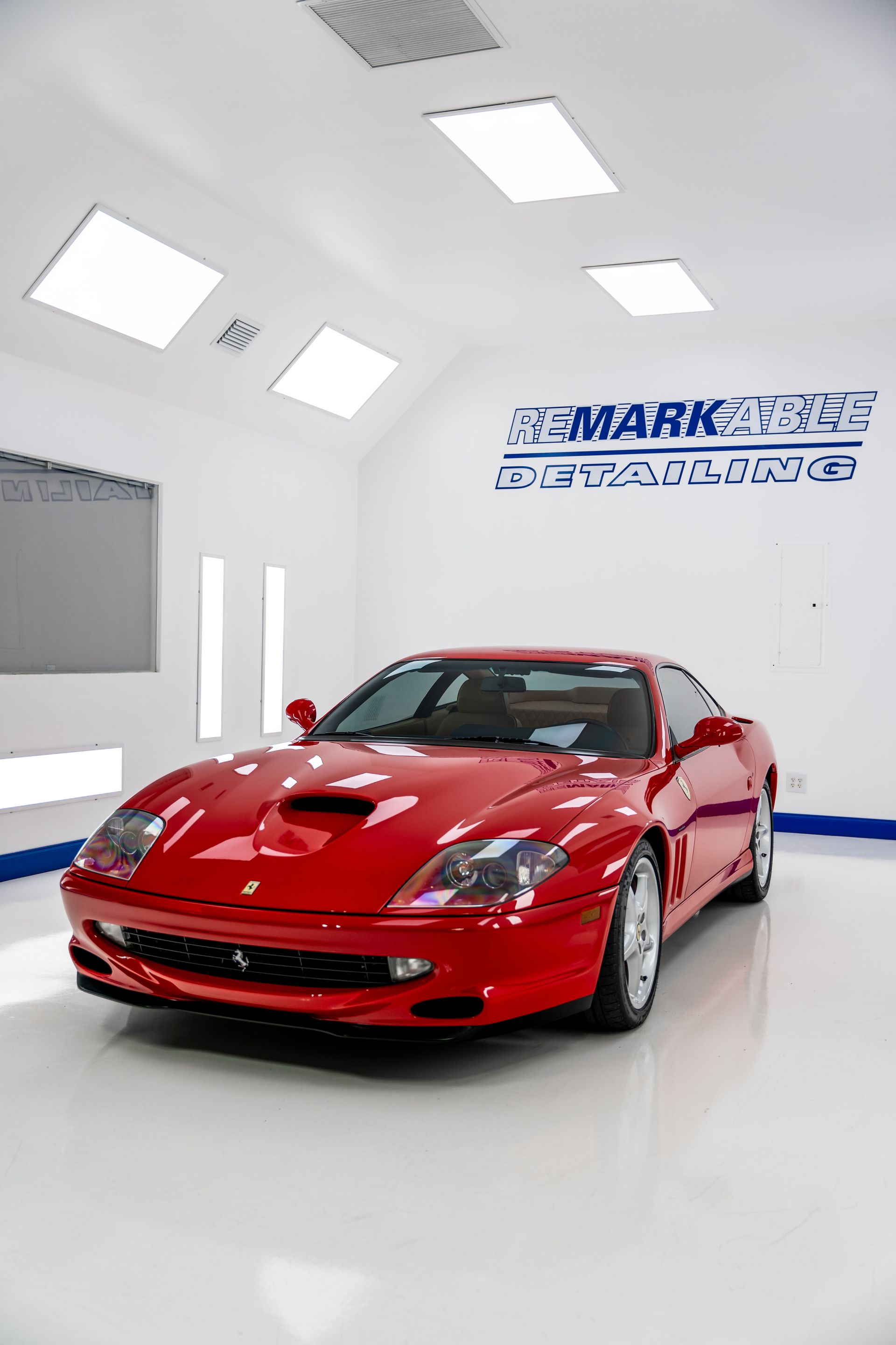 Red sports car in a bright white showroom with glossy floors and wall signage