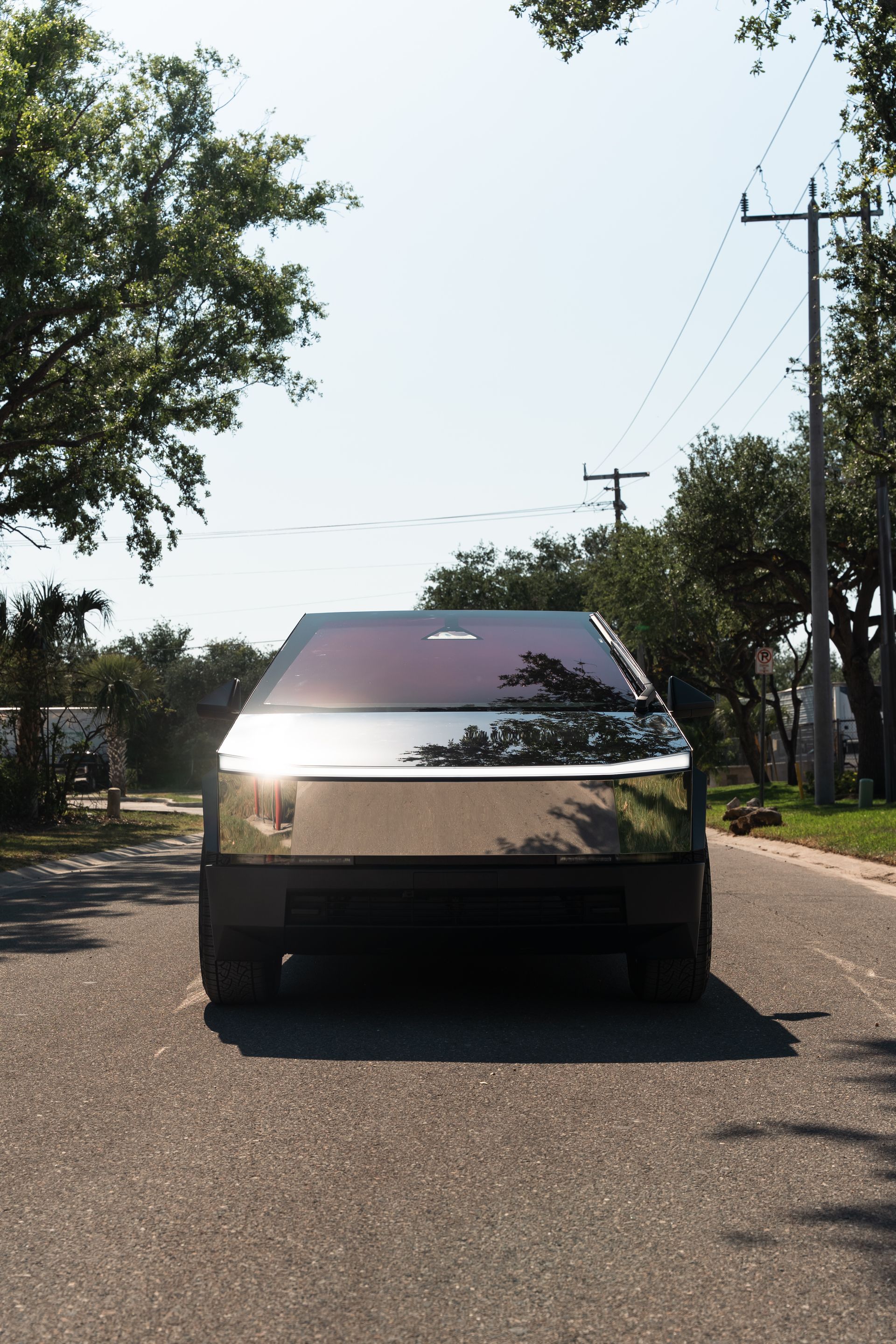 Front view of a silver pickup truck parked on a quiet road with trees and utility poles.