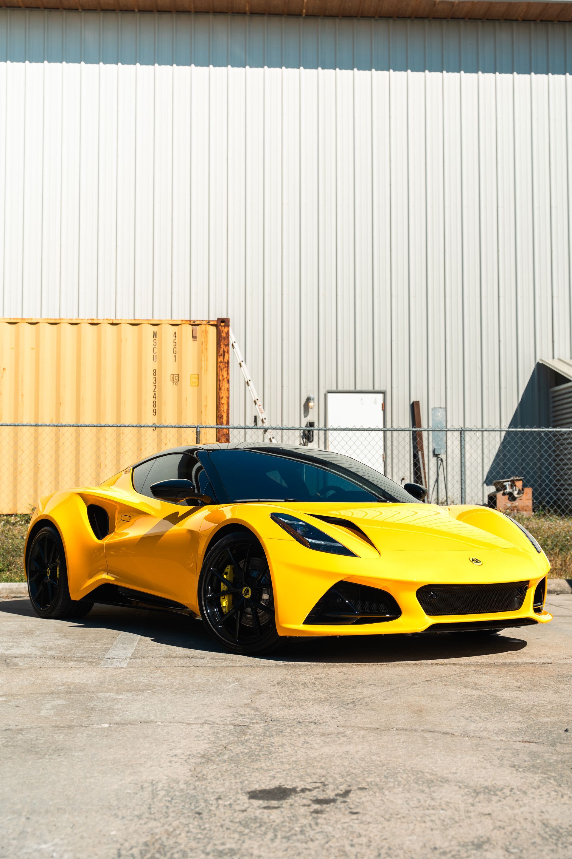 Yellow sports car parked in front of an industrial building.