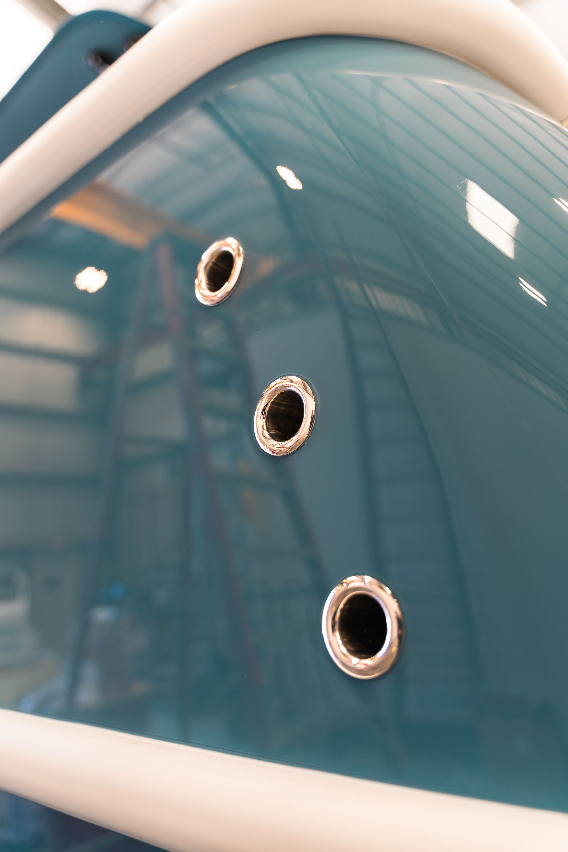 Blue glossy play structure with three circular porthole holes and white curved edges