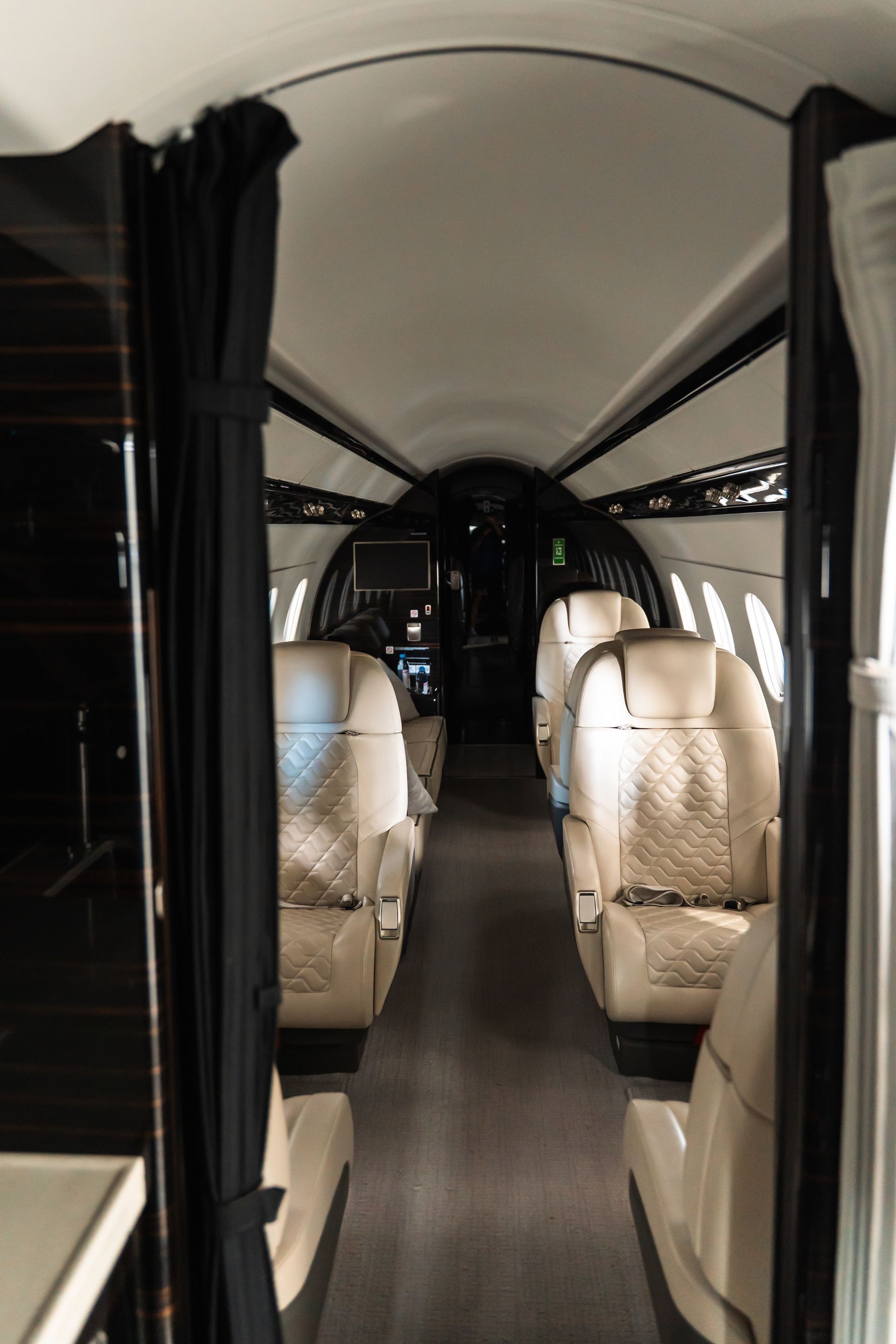 Interior of a luxury private jet cabin with beige leather seats and a narrow aisle
