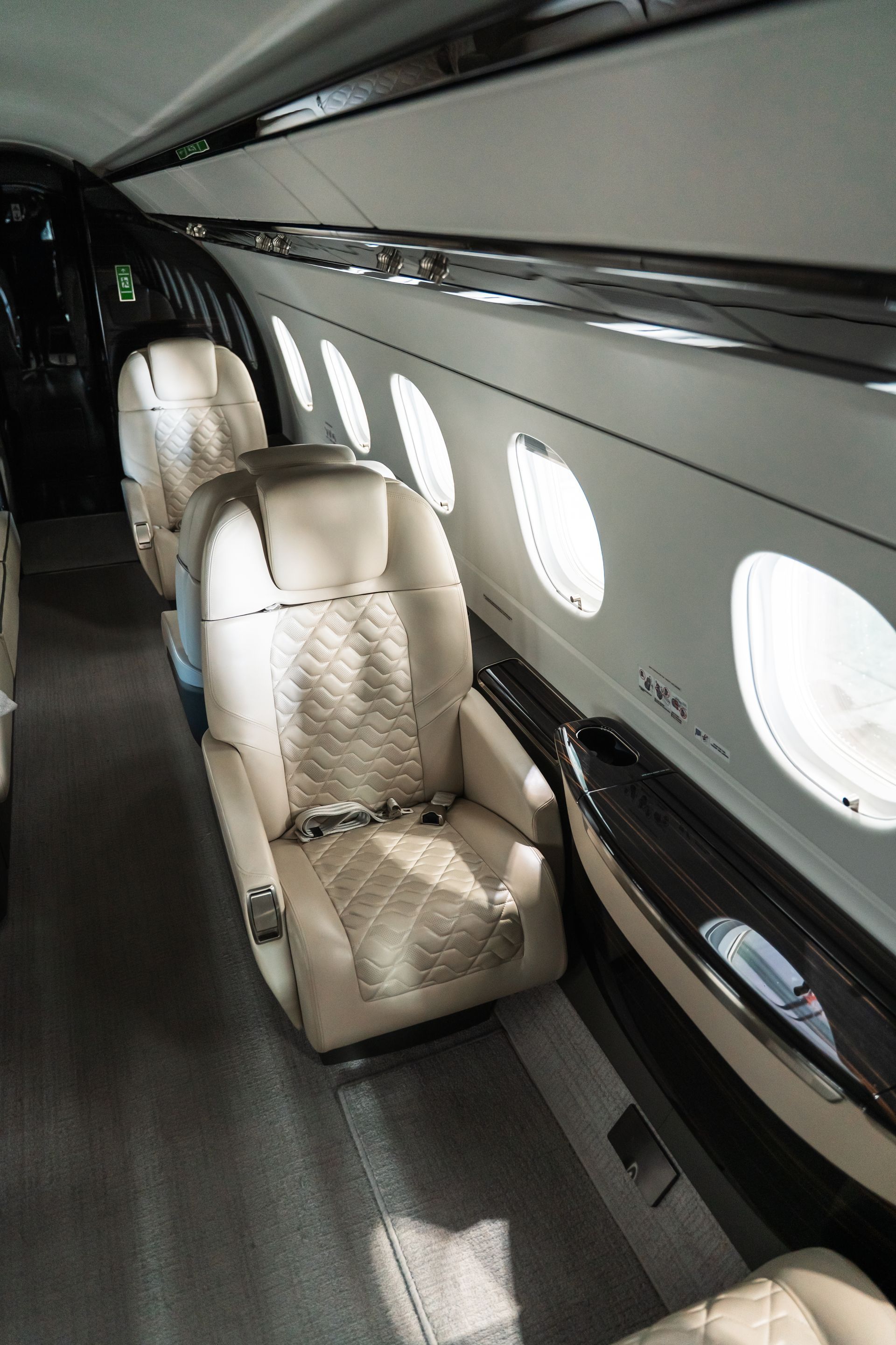 Luxurious private jet cabin with beige leather seats and oval windows along the wall