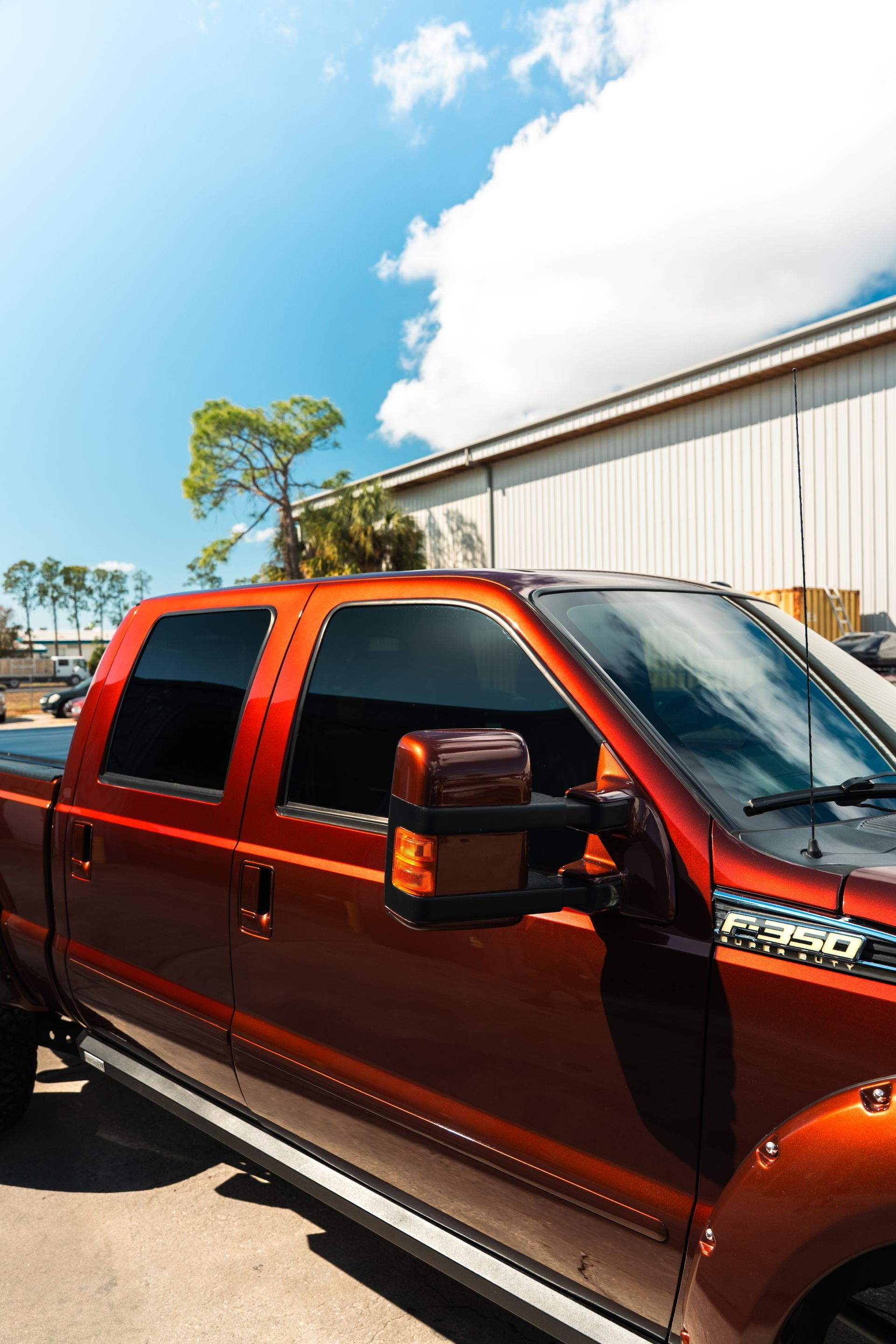 Orange pickup truck parked beside a warehouse under a bright blue sky