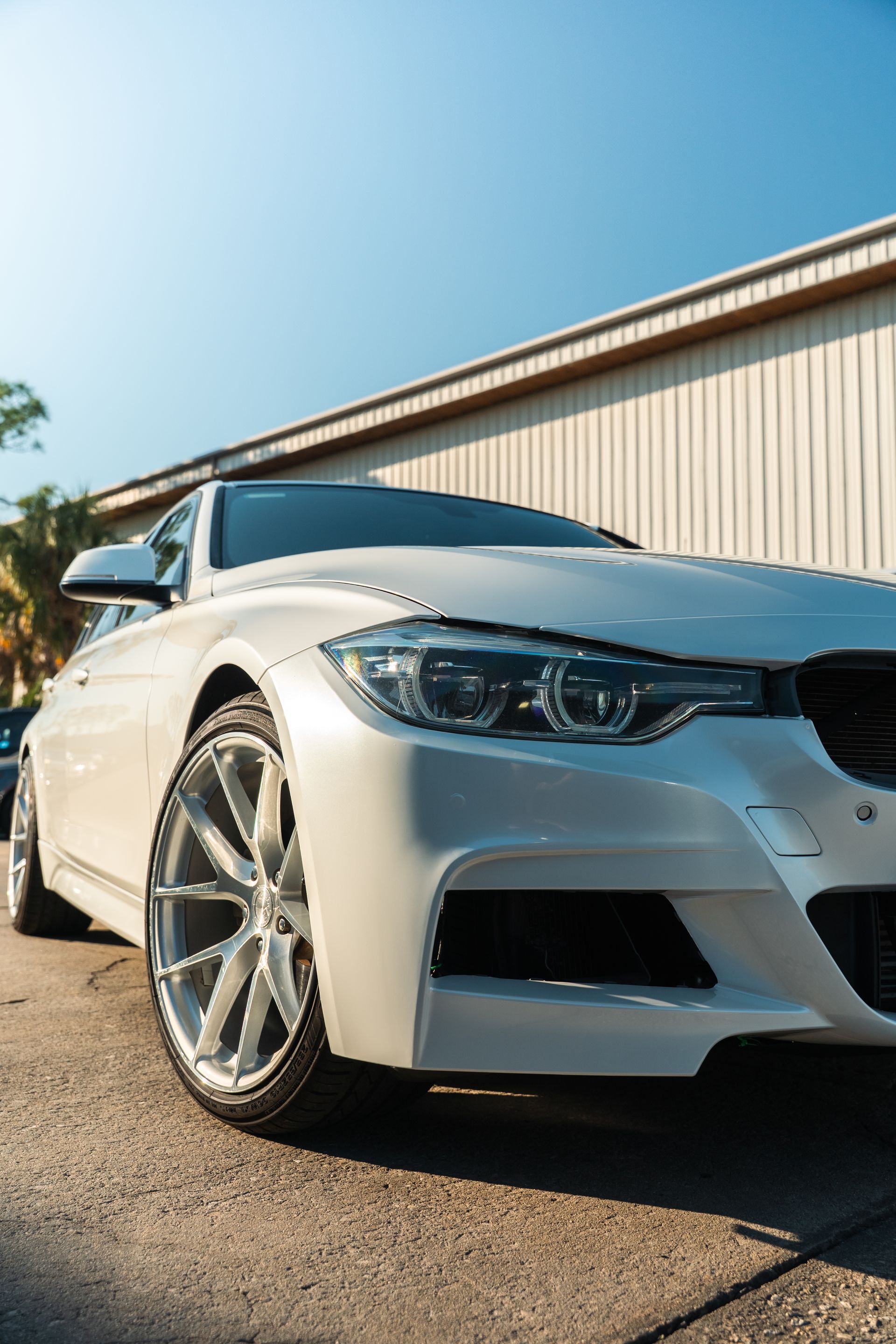 White BMW sedan parked beside a building under a clear blue sky