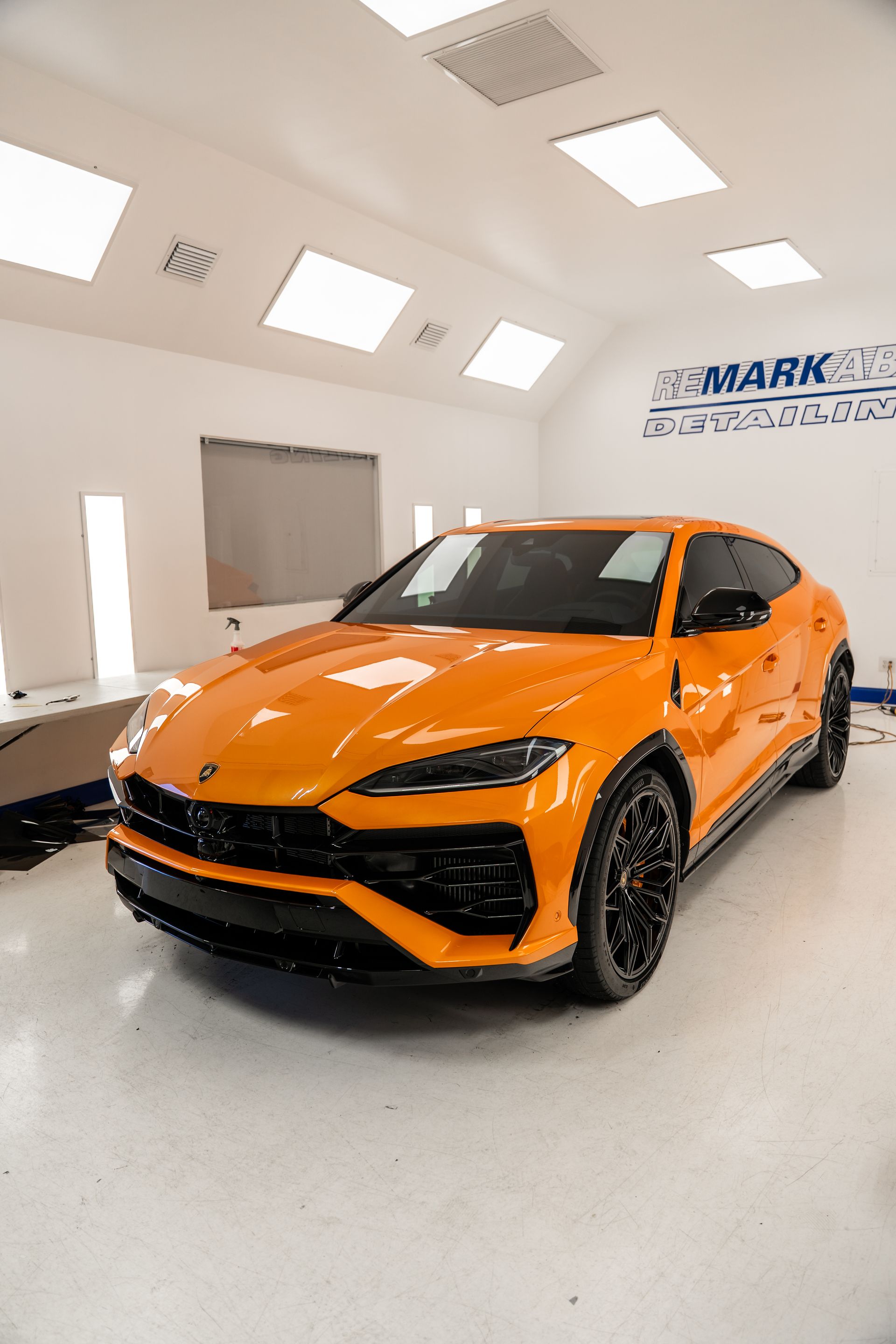 Orange sports car in a bright auto detailing shop with white walls and lights