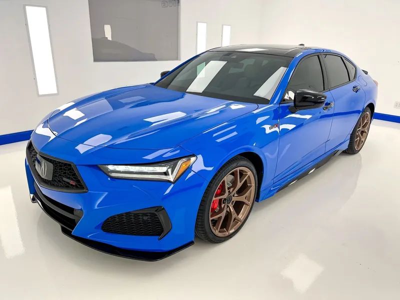 Blue sedan sports car in a studio, shown from the front-left angle