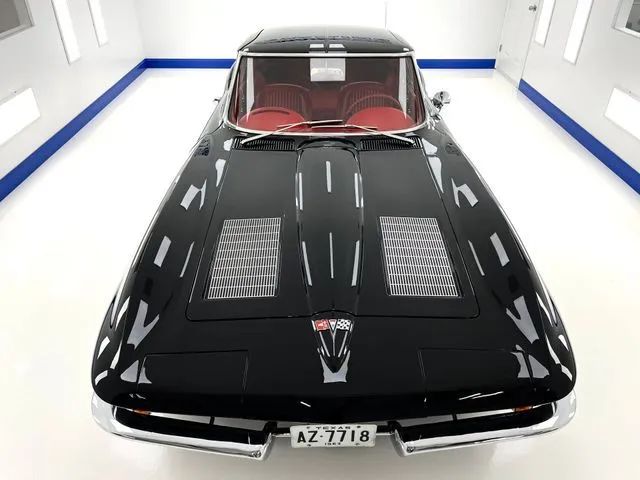Black classic car in a bright showroom, front view with red interior and hood vents