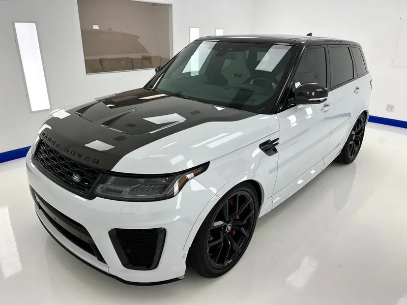 White SUV with black hood and wheels parked in a bright showroom