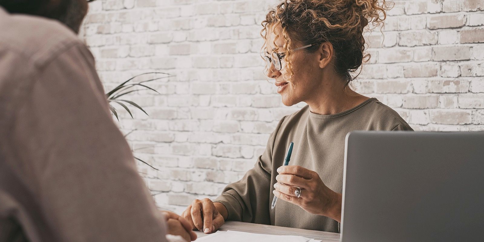 A man and a woman are sitting at a table with a laptop.