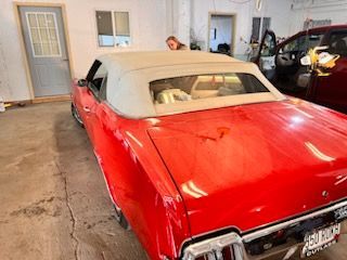 A red car with a white top is parked in a garage.
