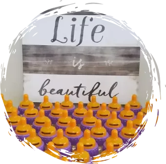 a sign that says life is beautiful is surrounded by purple pacifiers