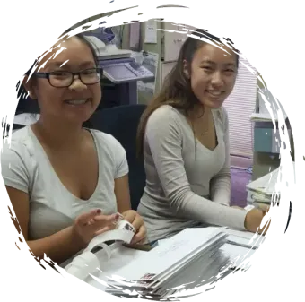 two women are sitting at a desk and smiling for the camera