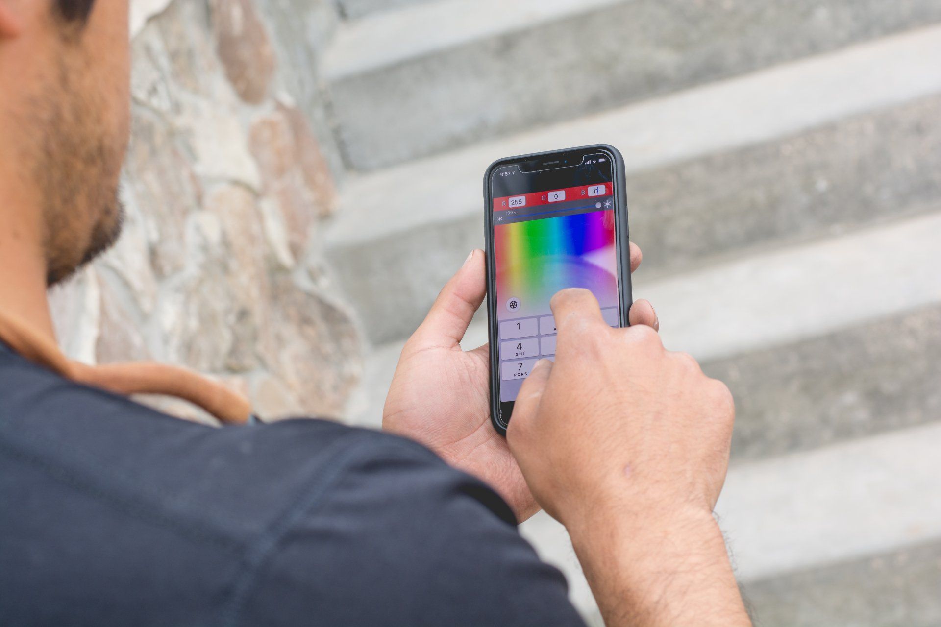 Person using a smartphone with a color wheel app near outdoor steps