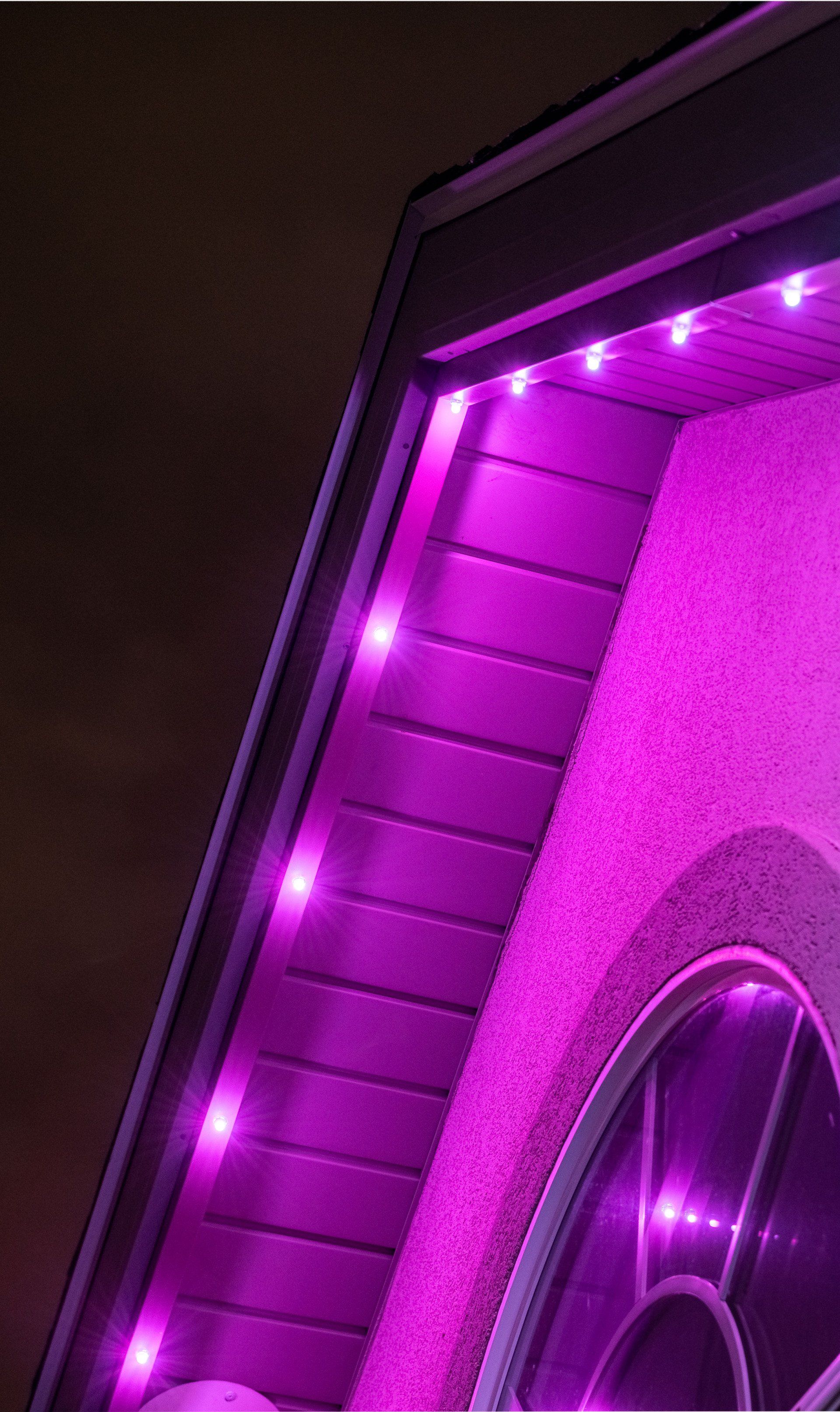 Close-up of a black car wheel with glowing purple LED lighting along the wheel well