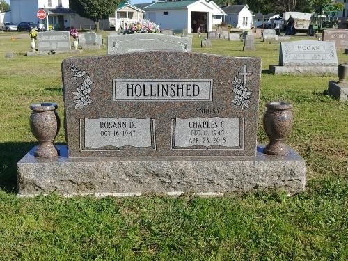 A granite cemetery headstone for the Hollinshed family, set in a grassy yard under a clear sky.