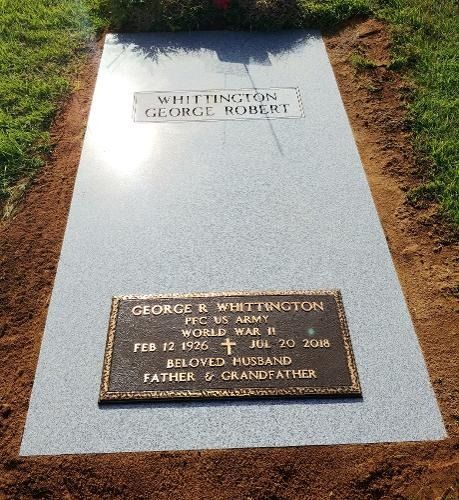 A gravestone with a gray granite marker and a bronze plaque for George R. Whittington, US Army, World War II.