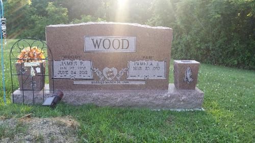 A granite headstone for the Wood family, featuring two names and dates, surrounded by grass with a small flower vase.