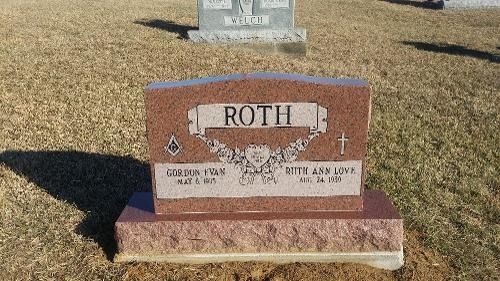 A polished red granite tombstone for the Roth family, featuring carved names and dates in a grassy cemetery.