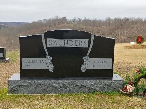A black granite tombstone engraved with the surname 