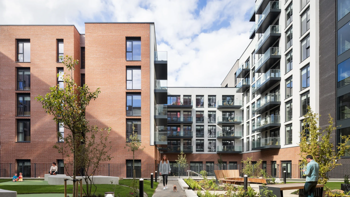 Modern apartment courtyard with brick and white buildings, trees, and people walking