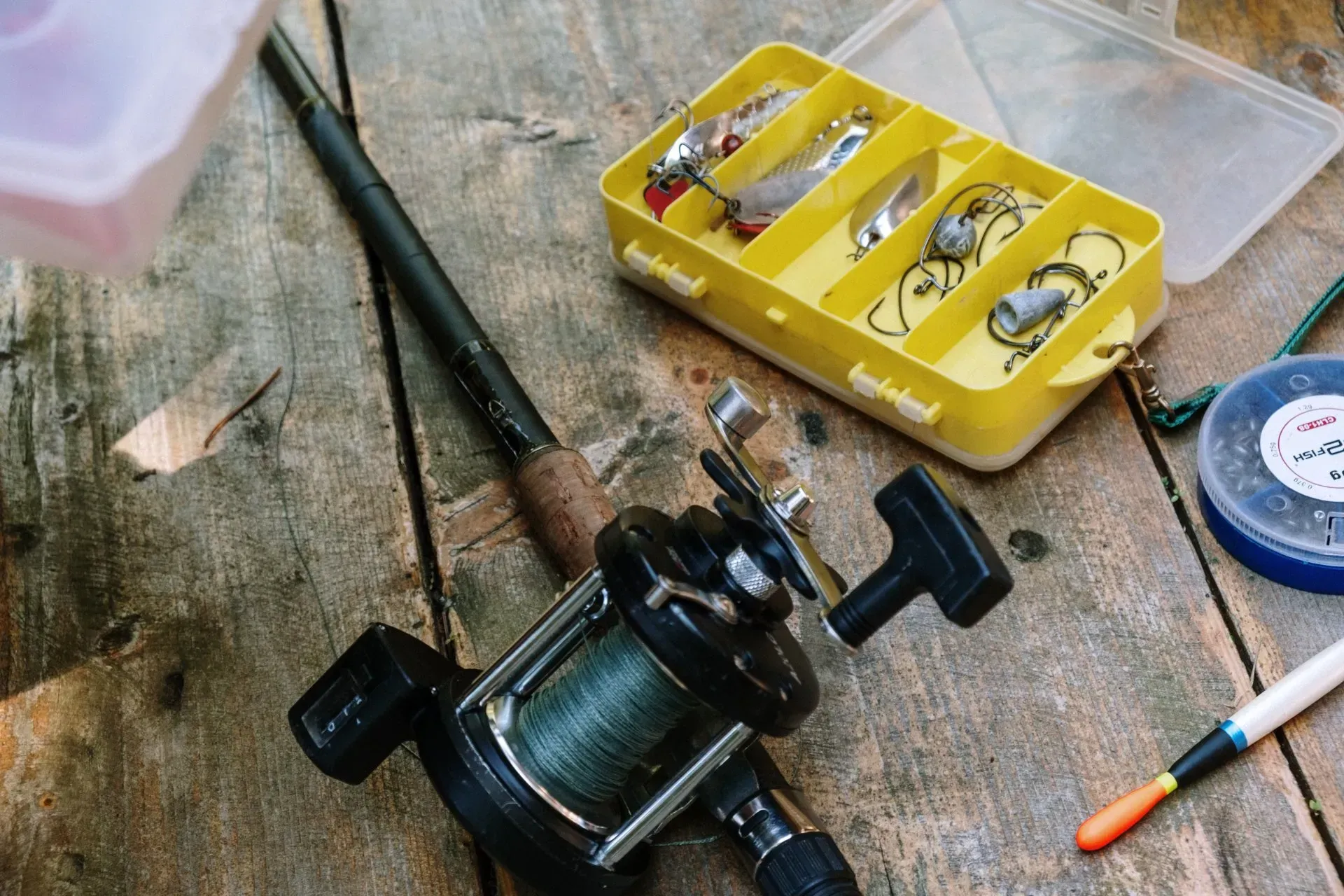 A fishing rod and reel are sitting on a wooden table.