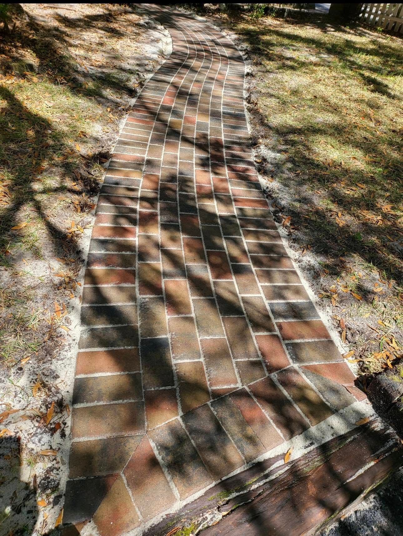 A brick walkway is being built in a backyard.