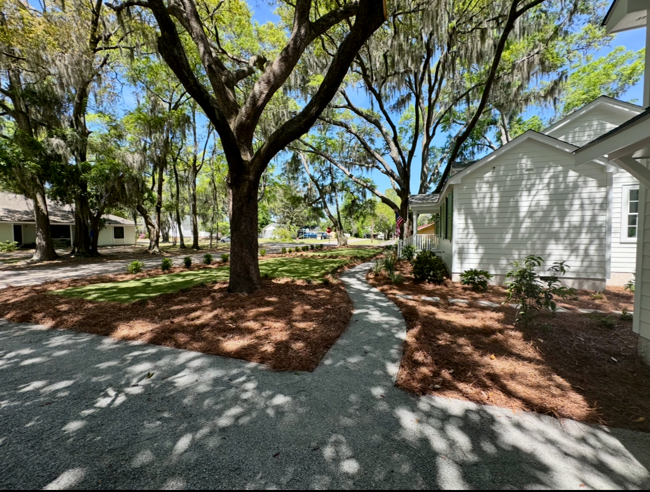 A path leading to a white house surrounded by trees