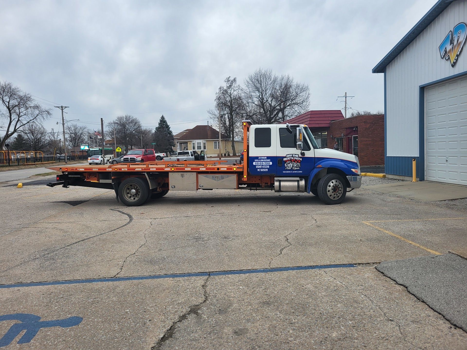 Blue flatbed truck parked outside a building on a cloudy day