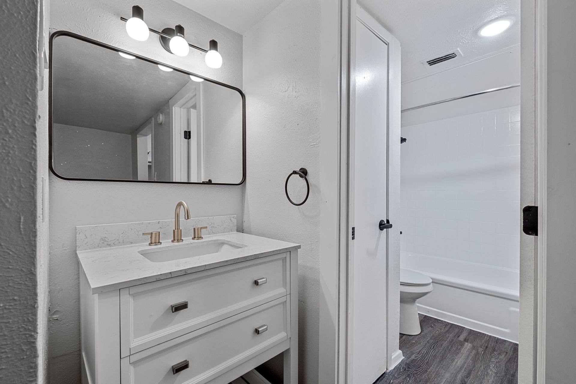 Photo showing a bathroom vanity with a separate door going to a toilet with a bathtub/shower combo next to it