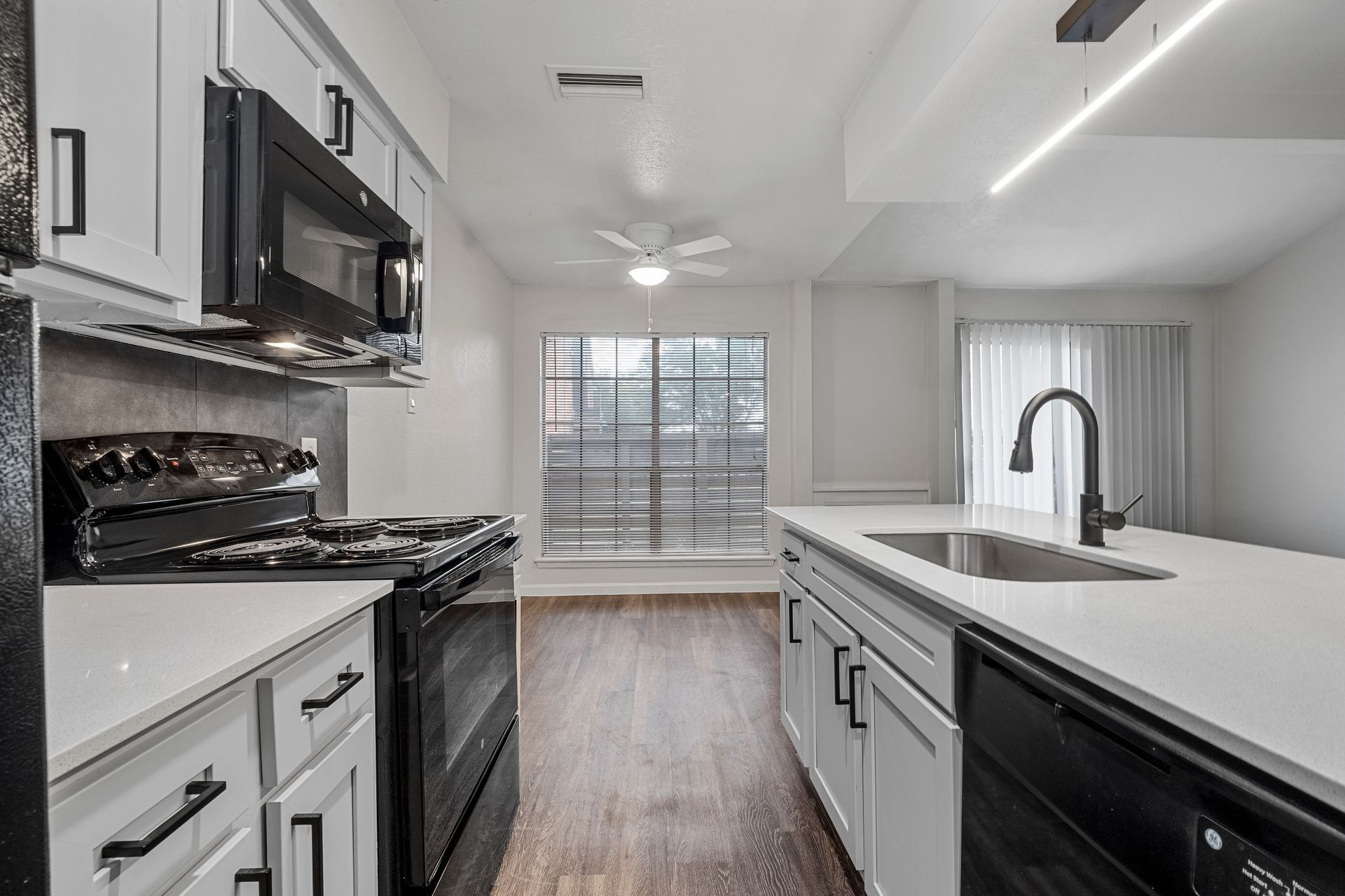 Photo showing a long kitchen with the dining area in the background