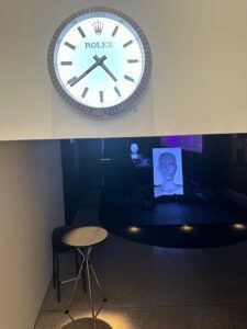 Horloge murale au-dessus d'une alcôve sombre avec un tabouret et un petit panneau d'affichage en dessous