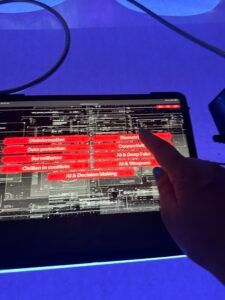 Main pointant vers une tablette affichant du texte rouge et blanc sur un écran sombre sous une lumière bleue
