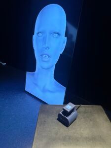 Écran holographique bleu au-dessus d'un petit appareil posé sur une table dans une pièce sombre