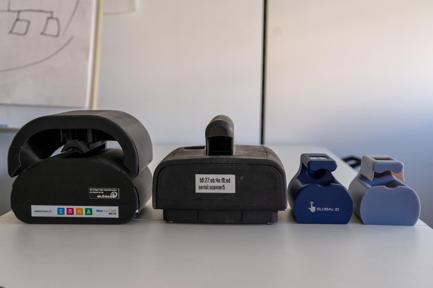 Quatre petites kettlebells alignées sur une table, noires et bleues avec des étiquettes.