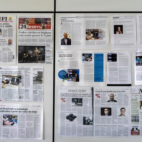 Mur de pages de journaux et de magazines agencées en collage, principalement en noir et blanc avec quelques photos en couleur