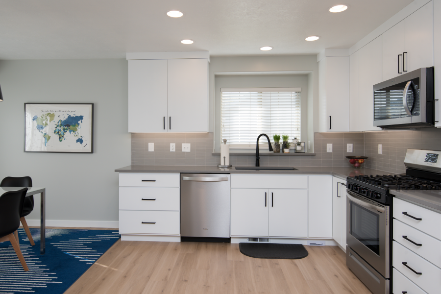Modern kitchen with white cabinets, stainless steel appliances, and gray countertops.