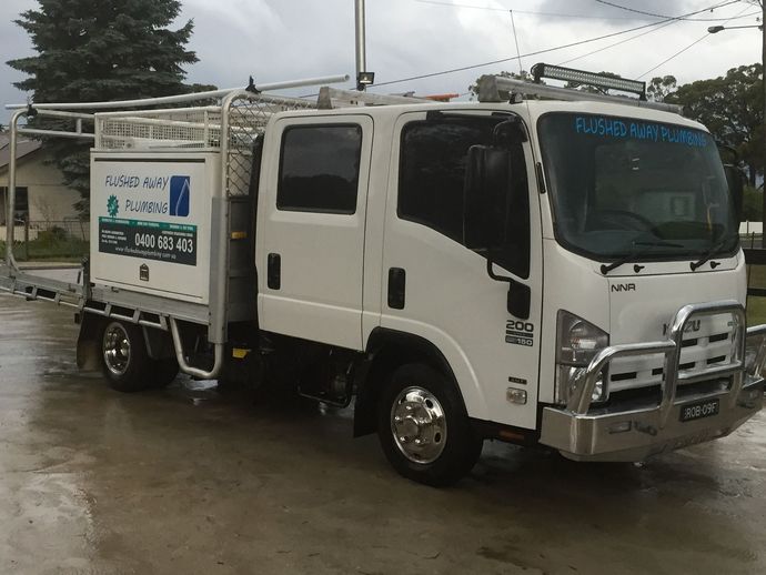 White utility truck parked on a wet road under cloudy skies