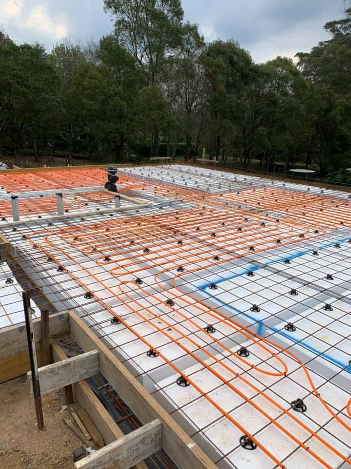 Construction site with orange pipes and white insulation laid over a floor slab outdoors