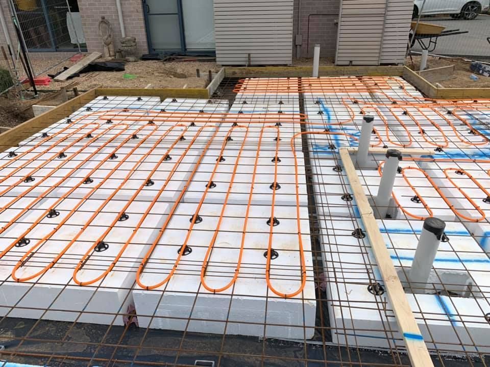 Partially built floor with white foam panels and orange radiant heating tubes on rebar mesh