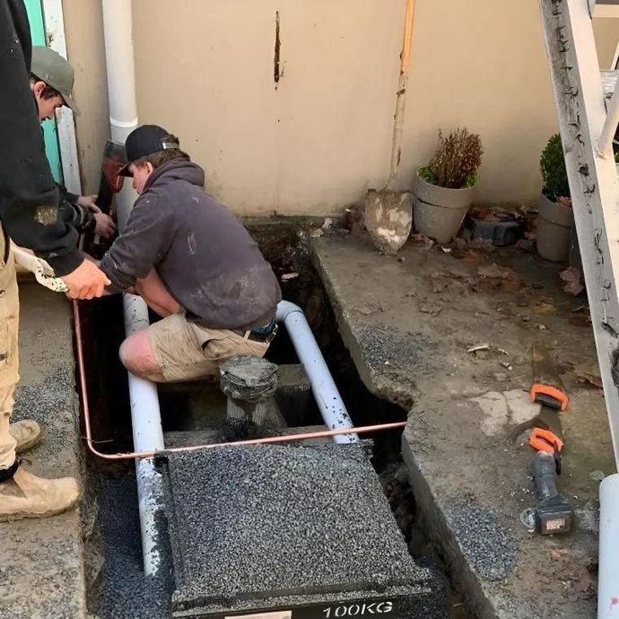 Workers installing a concrete ramp with metal rails beside a building entrance