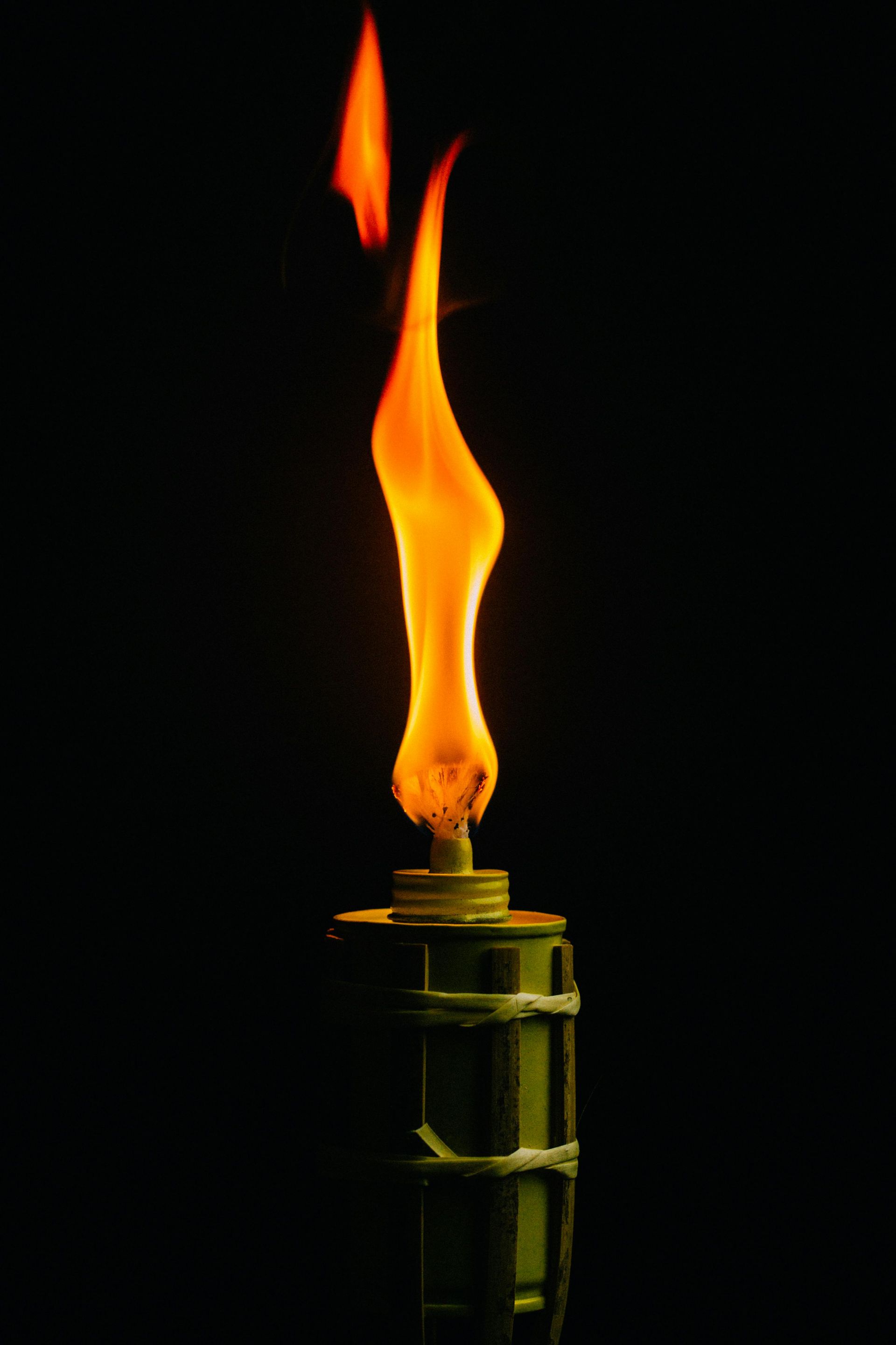 A lit torch with a bright orange flame against a black background