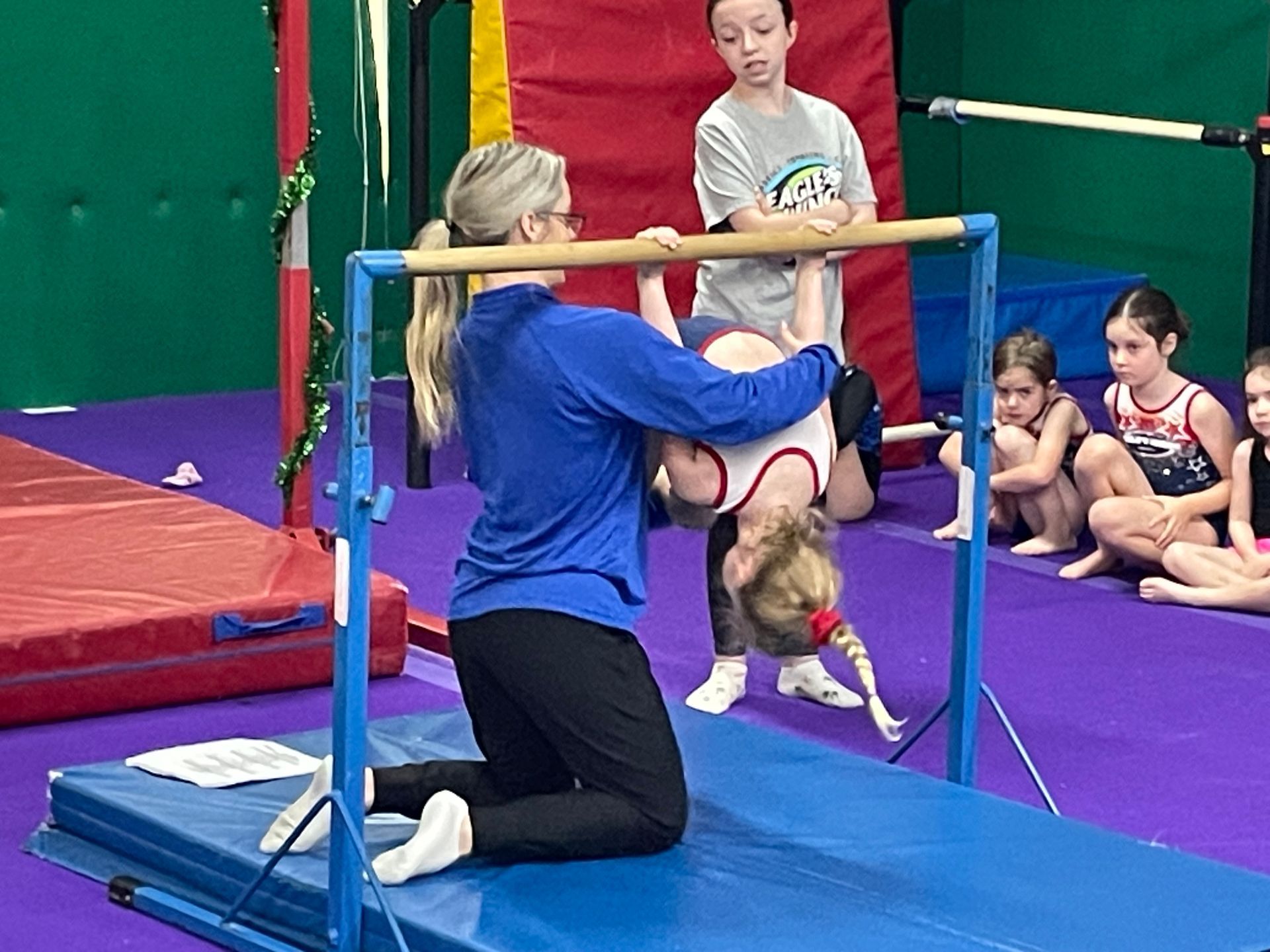 A woman is standing in front of a trampoline in a gym.
